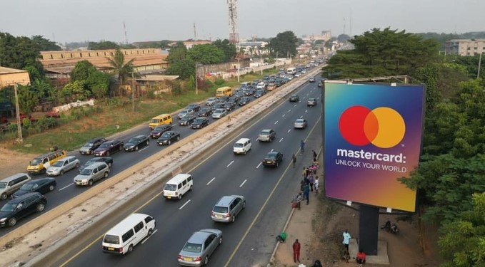 A front-lit static billboard located at Tollgate/7up by Magodo on the Lagos–Ibadan Expressway, facing traffic from Ojota. The board is double-sided and each side is rented separately.