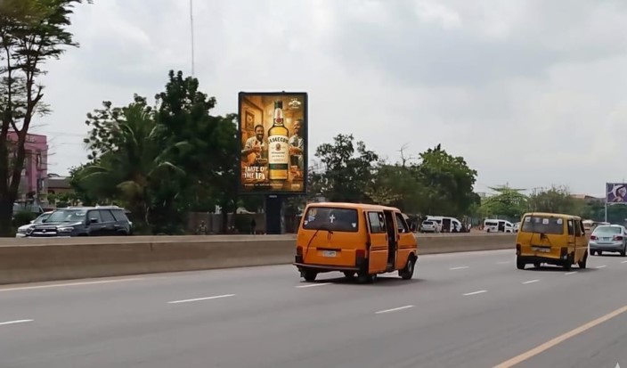A front-lit static billboard located at Tollgate/7up by Magodo on the Lagos–Ibadan Expressway, facing traffic from Berger The board is double-sided and each side is rented separately.